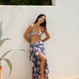 woman with black hair wearing a pareo in a navy and pink hibiscus print. 