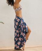 woman with black hair wearing a pareo in a navy and pink hibiscus print. 