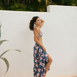 woman with black hair wearing a pareo in a navy and pink hibiscus print. 