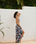 woman with black hair wearing a pareo in a navy and pink hibiscus print. 