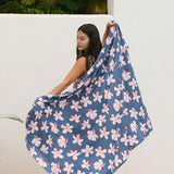 woman with black hair wearing a pareo in a navy and pink hibiscus print. 