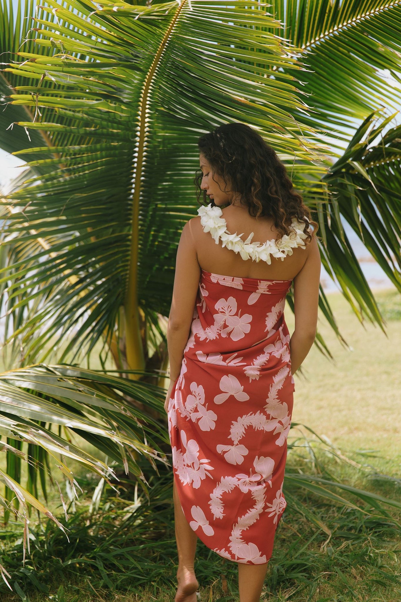 woman with brown hair wearing red pareo with light pink ginger + lei print