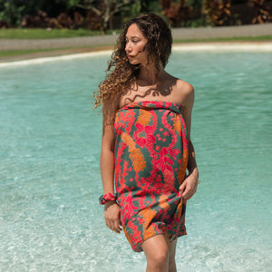 woman with brown hair wearing a colorful pareo with tropical lei print