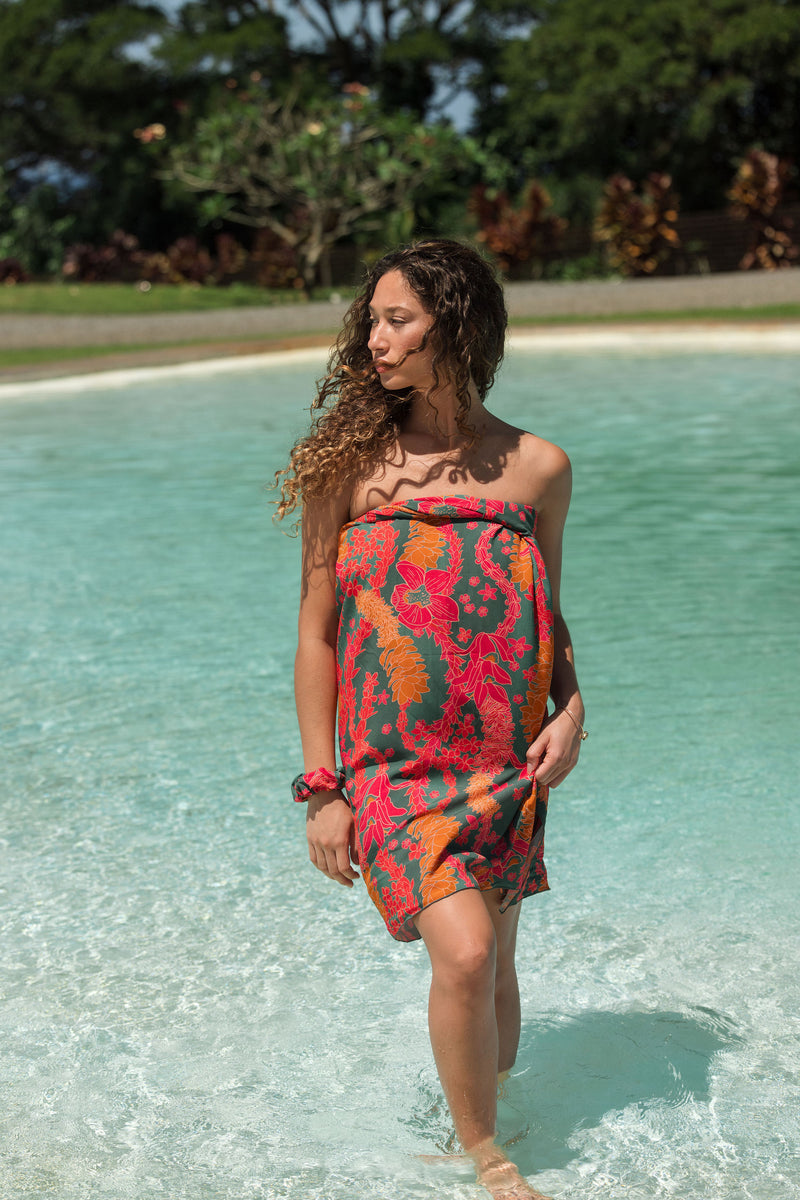 woman with brown hair wearing a colorful pareo with tropical lei print