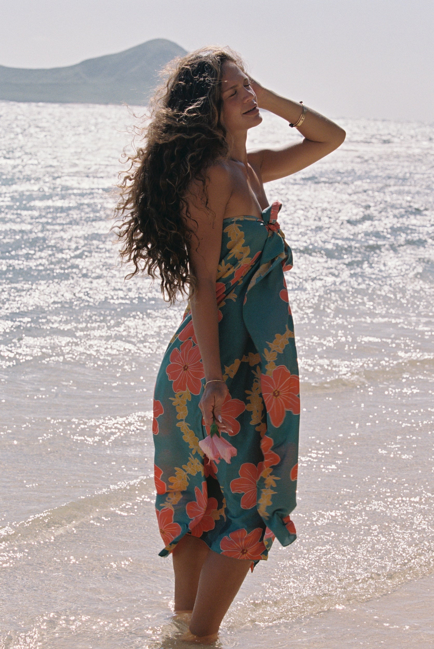 woman with brown hair wearing green pareo with orange and yellow lei pua print