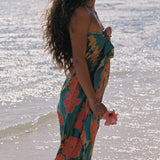 woman with brown hair wearing green pareo with orange and yellow lei pua print