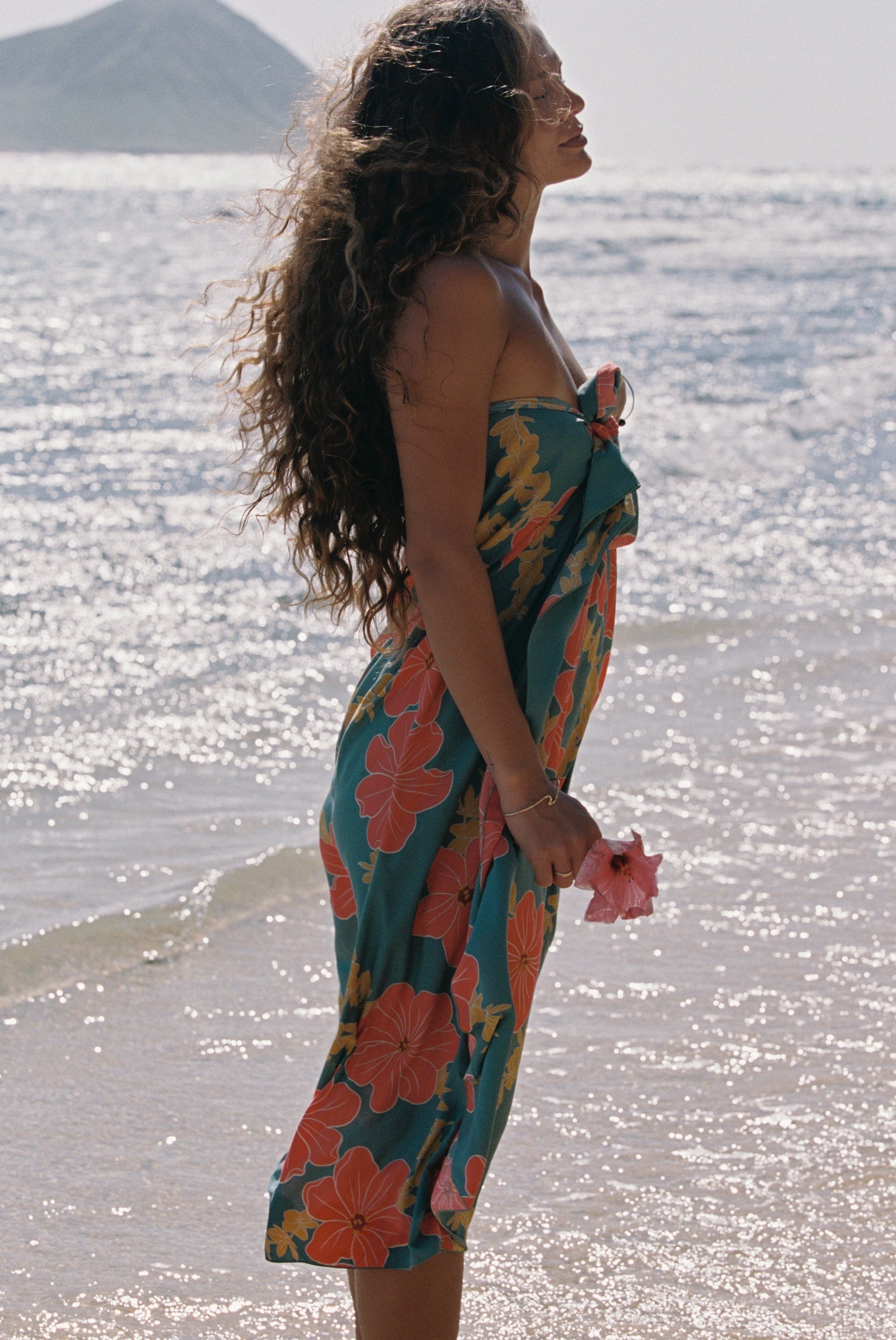 woman with brown hair wearing green pareo with orange and yellow lei pua print