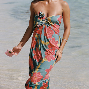 woman with brown hair wearing green pareo with orange and yellow lei pua print