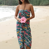 woman with brown hair wearing a dark teal pareo with shell lei print