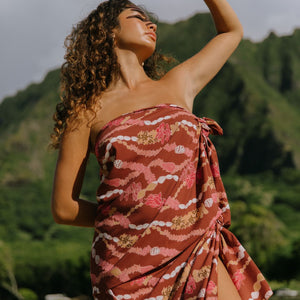 woman with brown hair wearing red brown pareo with lei print