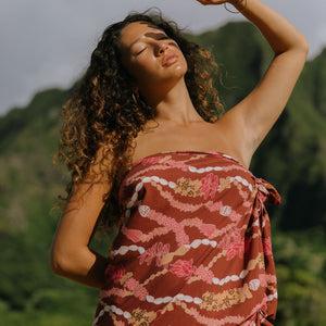 woman with brown hair wearing red brown pareo with lei print