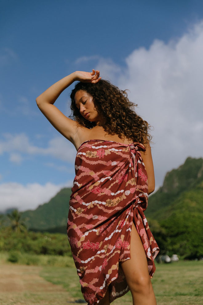 woman with brown hair wearing red brown pareo with lei print