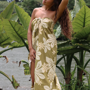 woman with brown hair wearing a pareo in a green color with naupaka pattern throughout. 