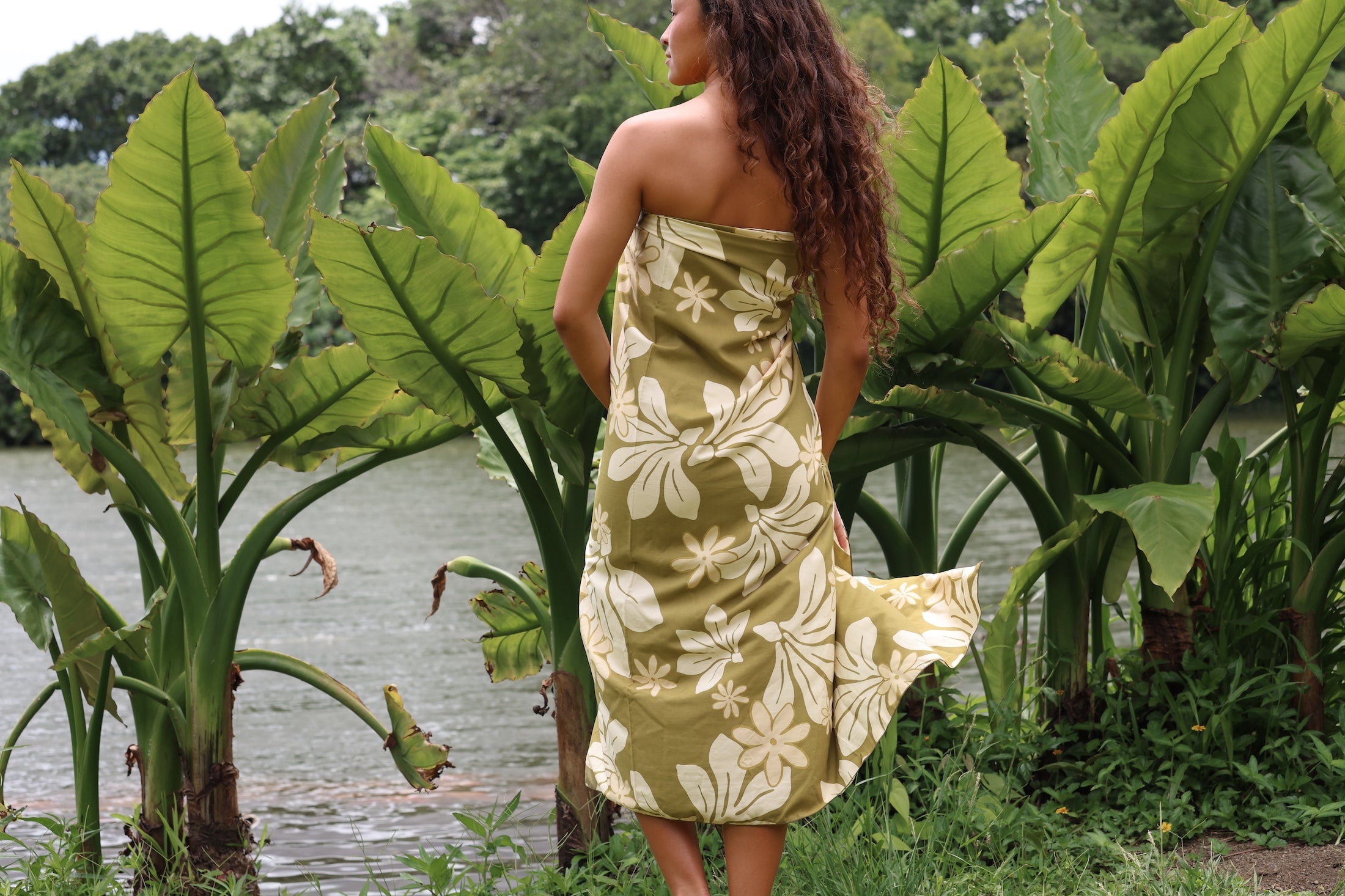 woman with brown hair wearing a pareo in a green color with naupaka pattern throughout. 