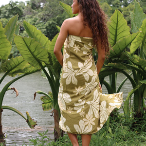 woman with brown hair wearing a pareo in a green color with naupaka pattern throughout. 