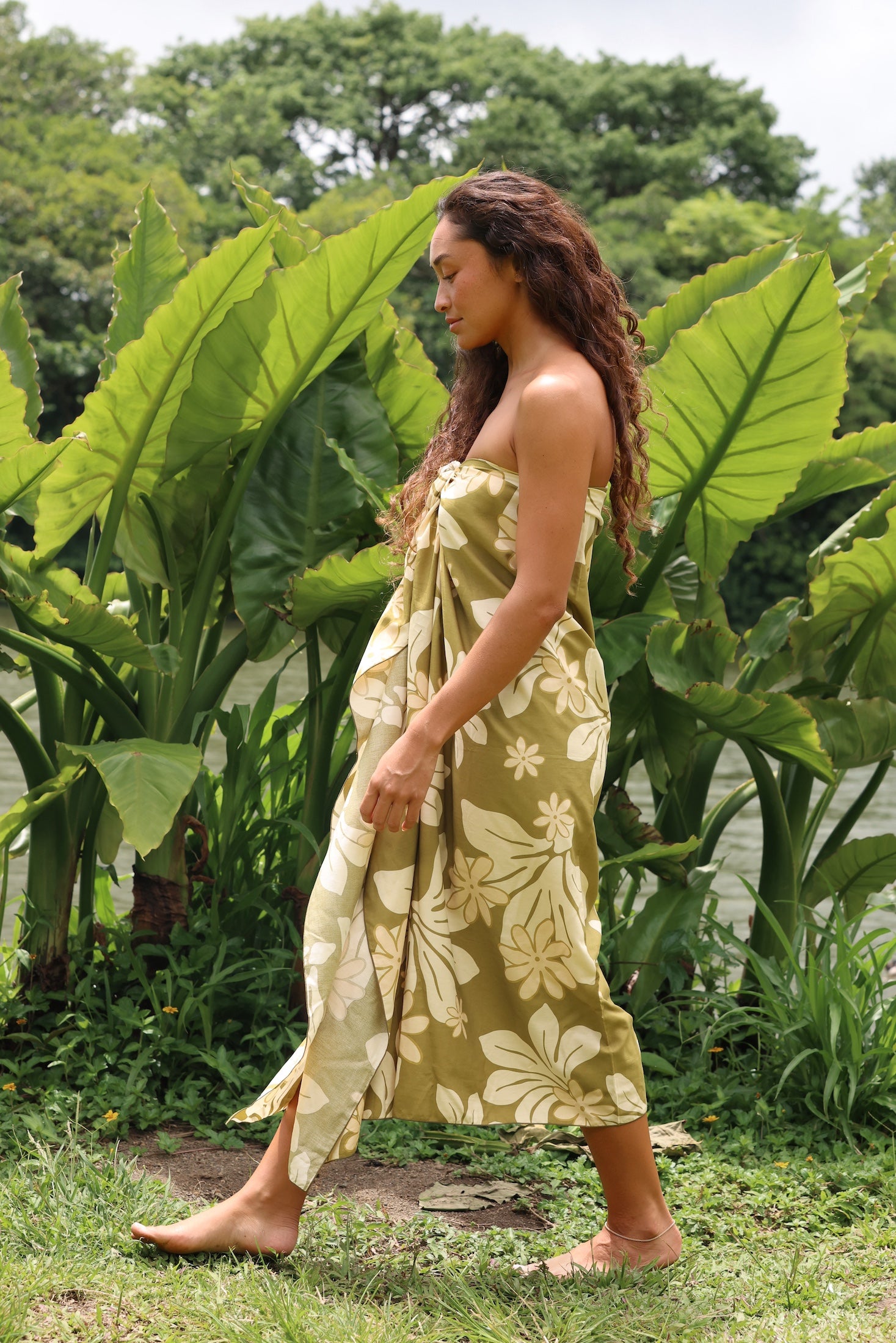 woman with brown hair wearing a pareo in a green color with naupaka pattern throughout. 