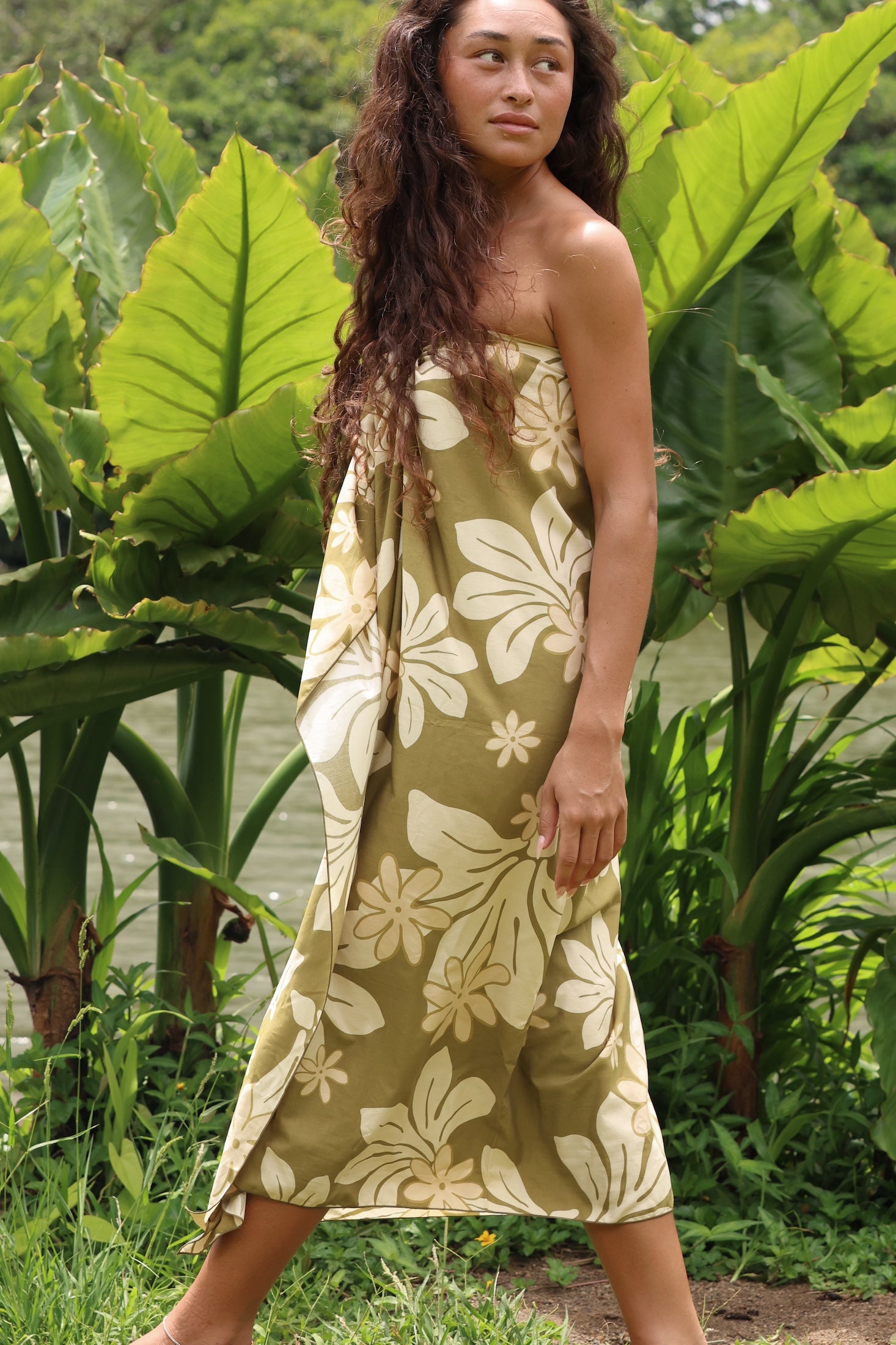woman with brown hair wearing a pareo in a green color with naupaka pattern throughout. 