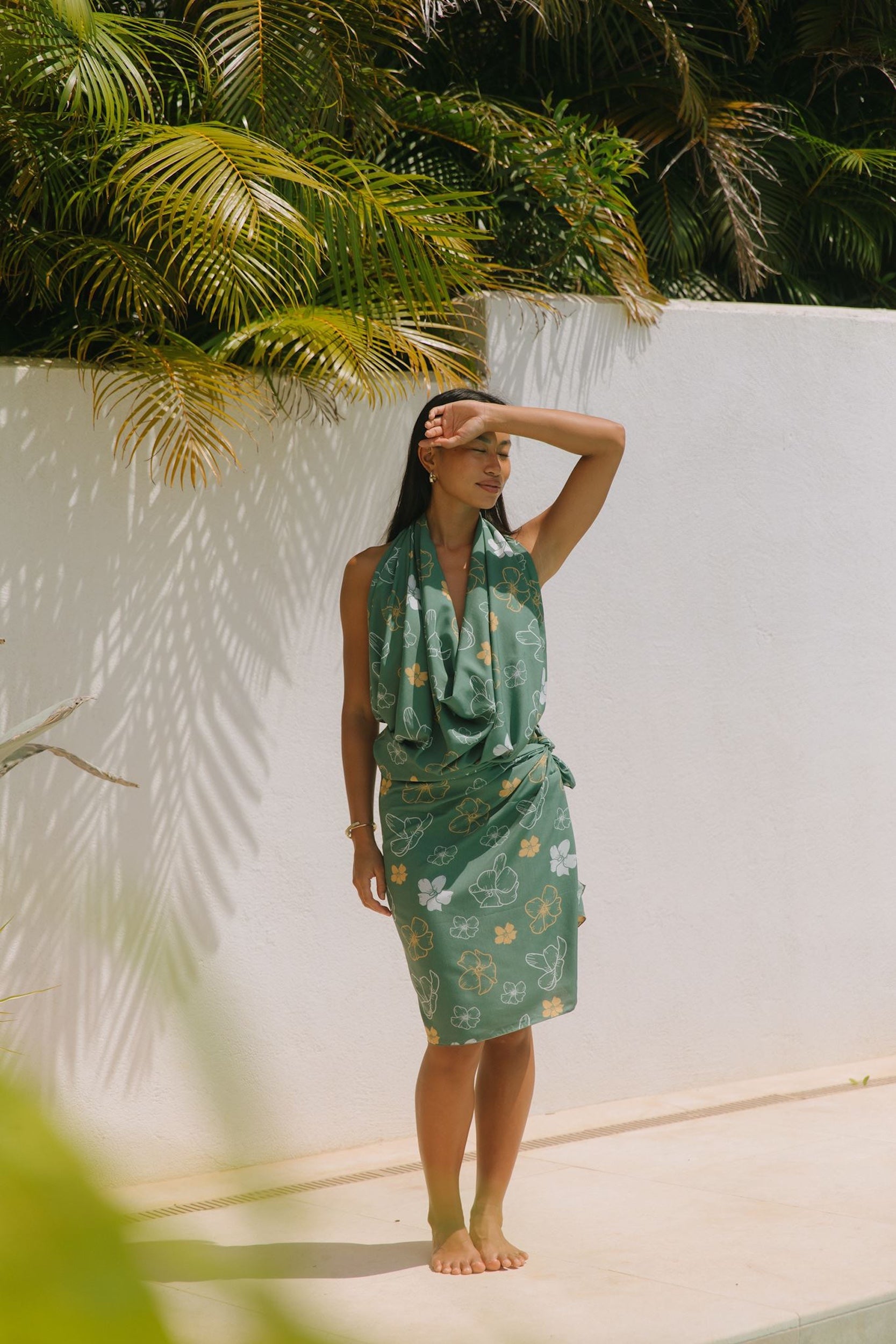 woman with brown hair wearing lush green pareo with puakenikeni print