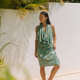 woman with brown hair wearing lush green pareo with puakenikeni print