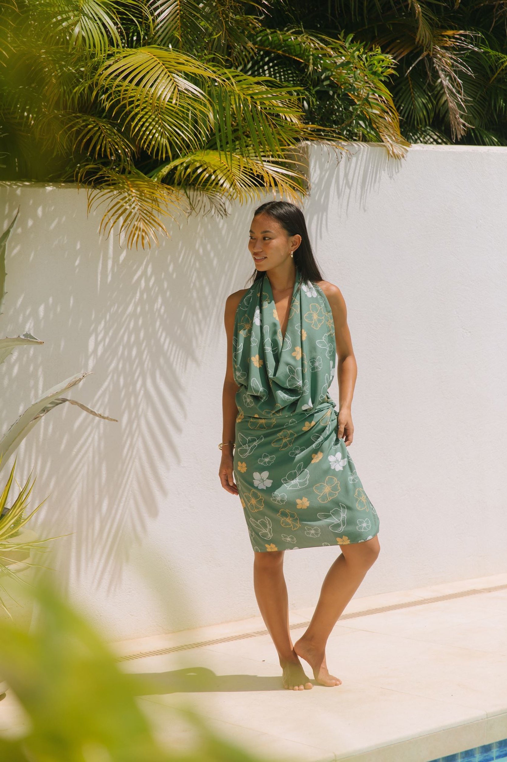 woman with brown hair wearing lush green pareo with puakenikeni print