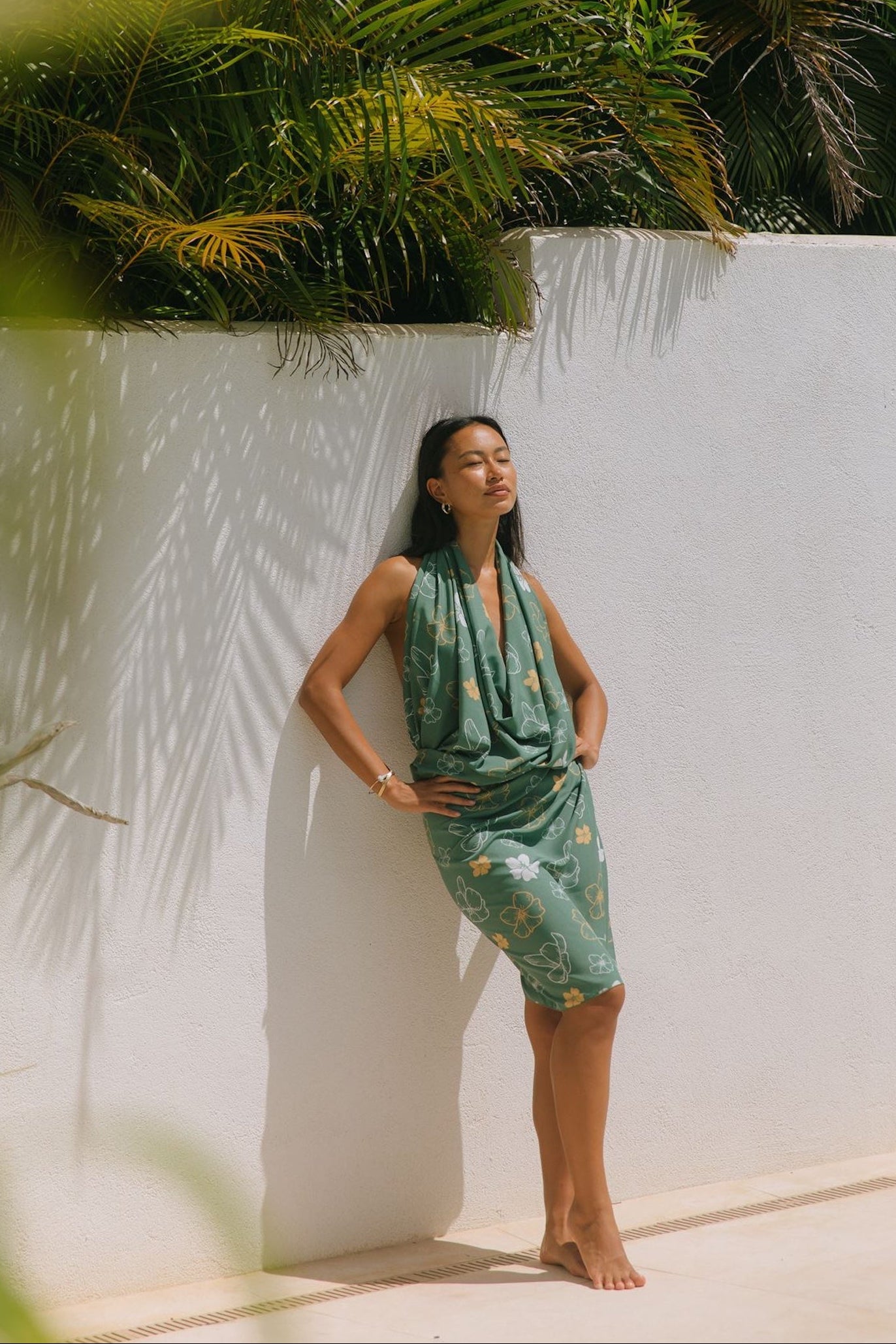 woman with brown hair wearing lush green pareo with puakenikeni print