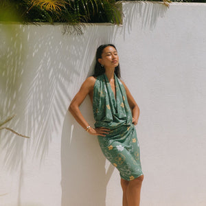 woman with brown hair wearing lush green pareo with puakenikeni print