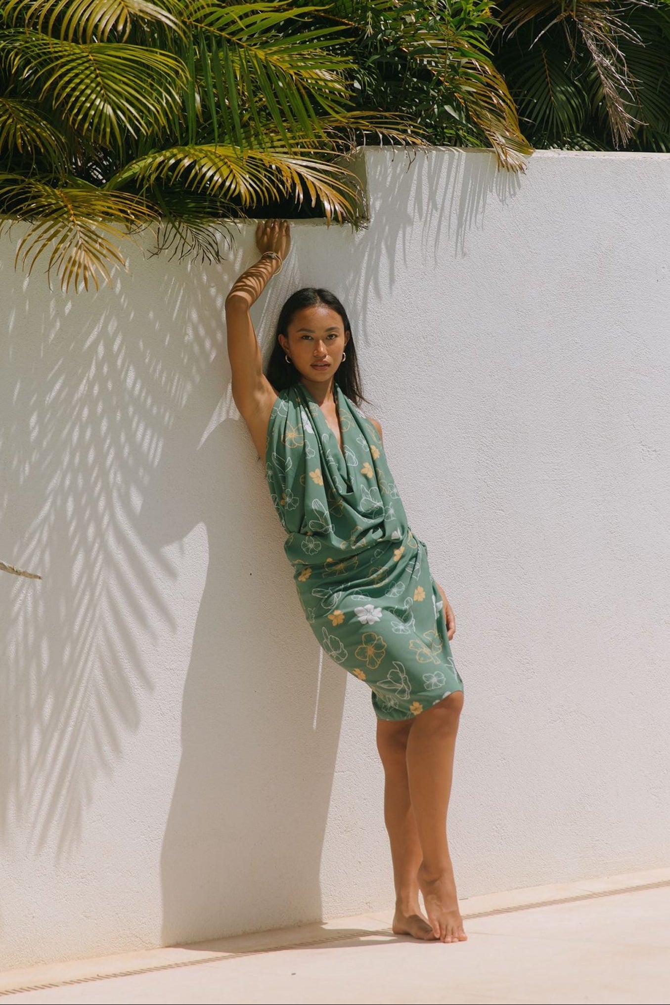woman with brown hair wearing lush green pareo with puakenikeni print