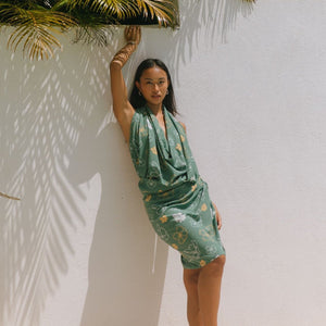 woman with brown hair wearing lush green pareo with puakenikeni print