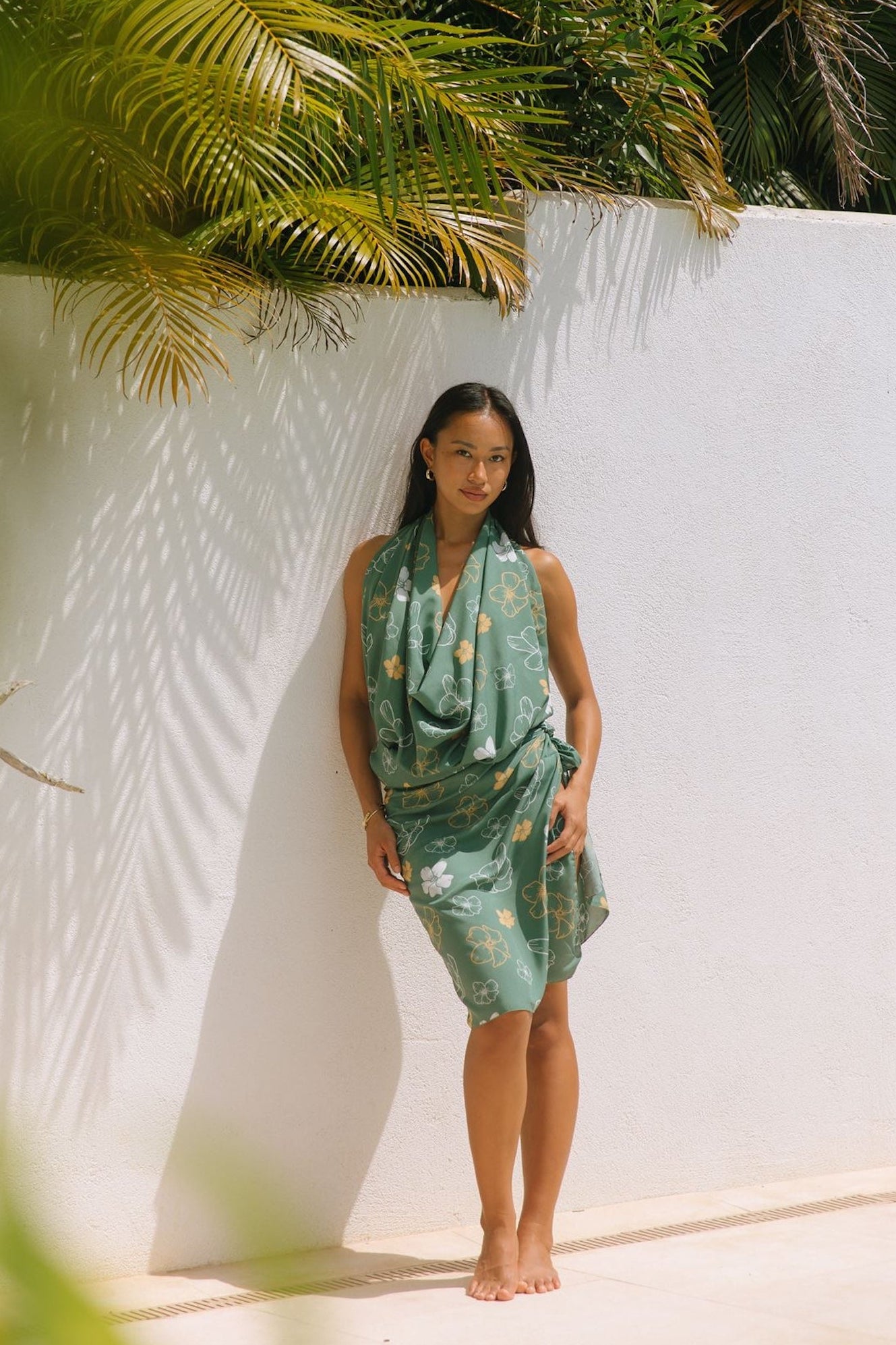 woman with brown hair wearing lush green pareo with puakenikeni print