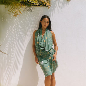 woman with brown hair wearing lush green pareo with puakenikeni print