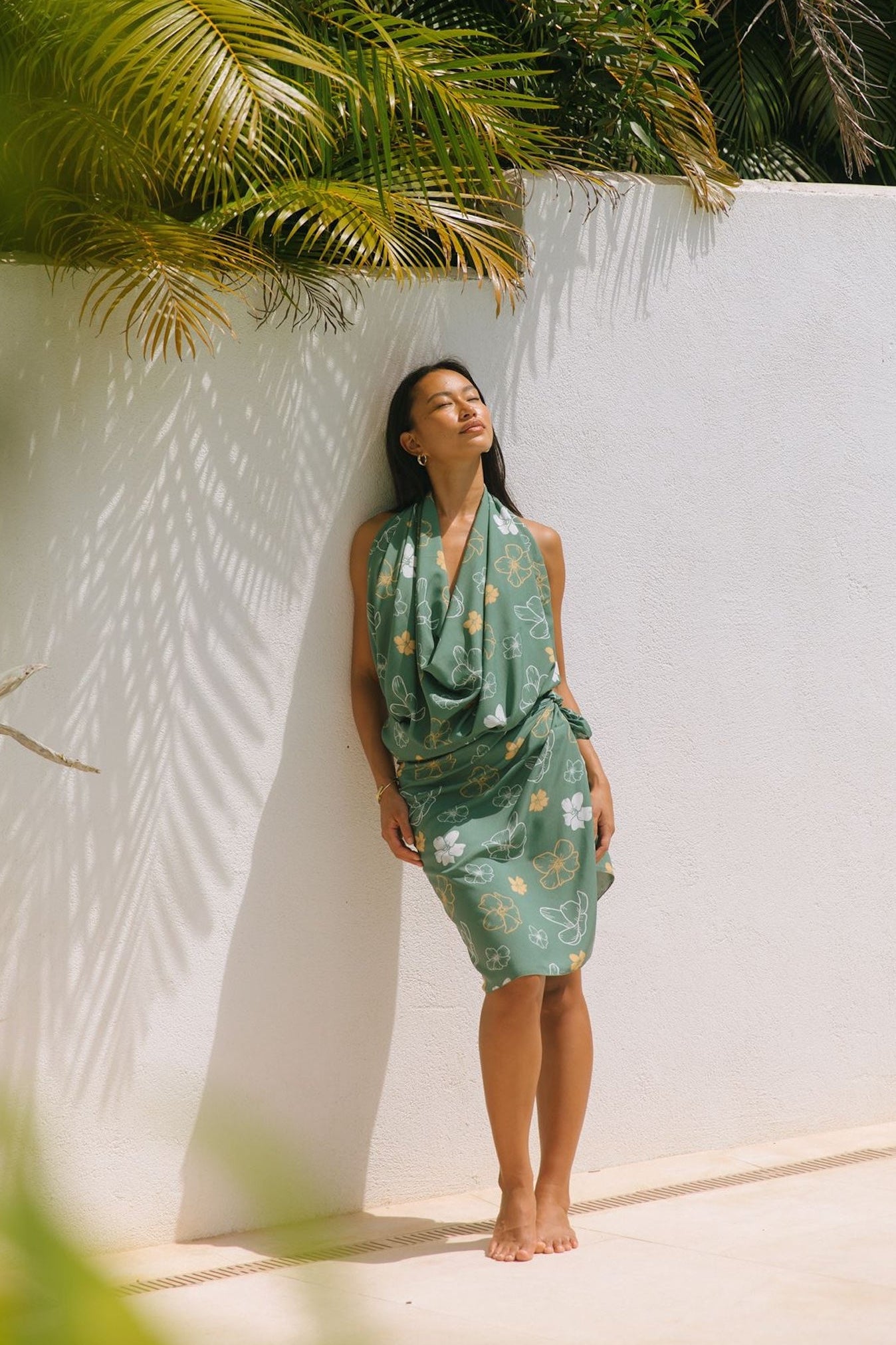 woman with brown hair wearing lush green pareo with puakenikeni print
