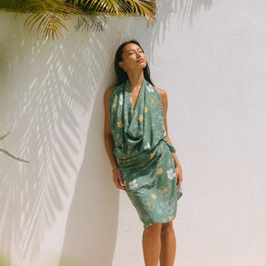 woman with brown hair wearing lush green pareo with puakenikeni print