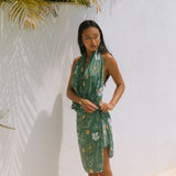 woman with brown hair wearing lush green pareo with puakenikeni print