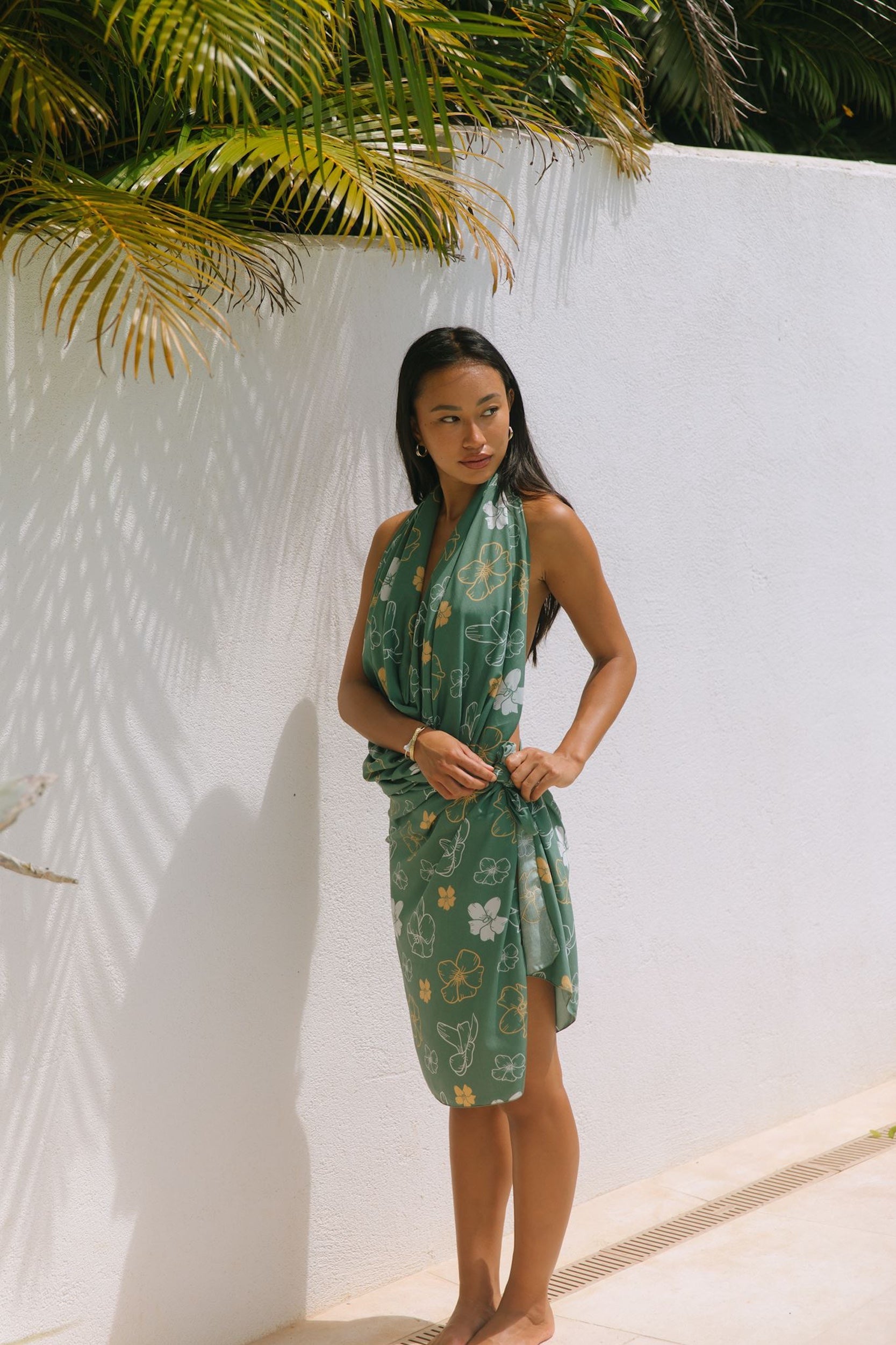 woman with brown hair wearing lush green pareo with puakenikeni print