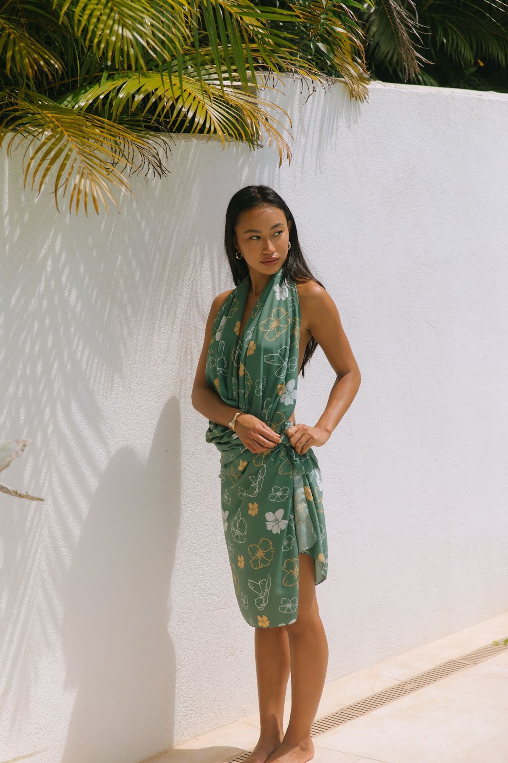 woman with brown hair wearing lush green pareo with puakenikeni print