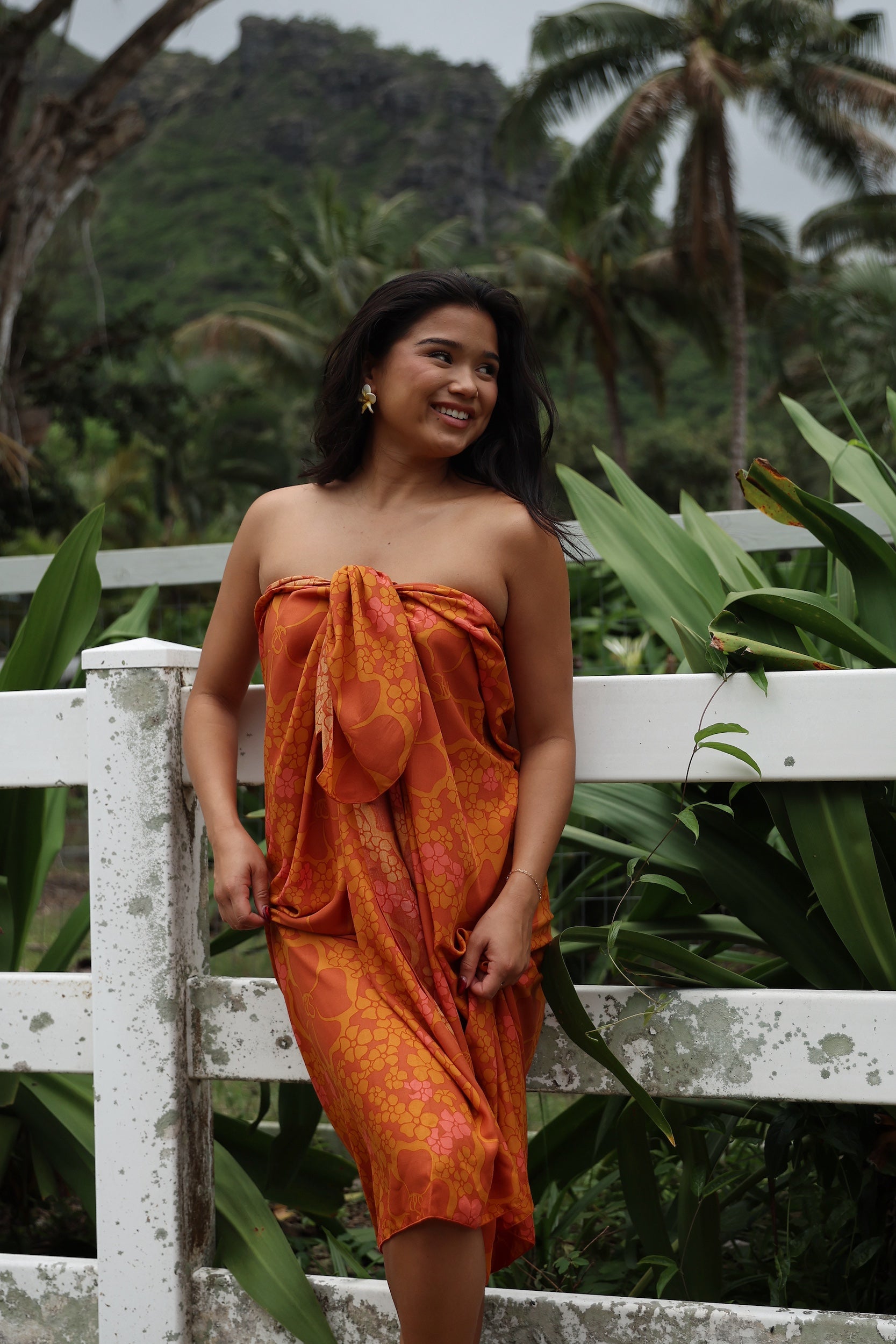 woman with brown hair wearing an orange puakenikeni pareo