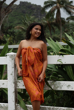 woman with brown hair wearing an orange puakenikeni pareo