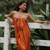 woman with brown hair wearing an orange puakenikeni pareo