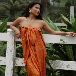 woman with brown hair wearing an orange puakenikeni pareo