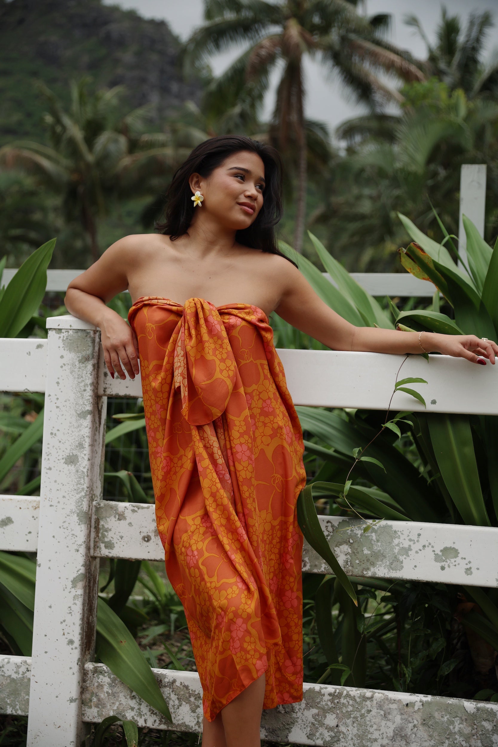 woman with brown hair wearing an orange puakenikeni pareo