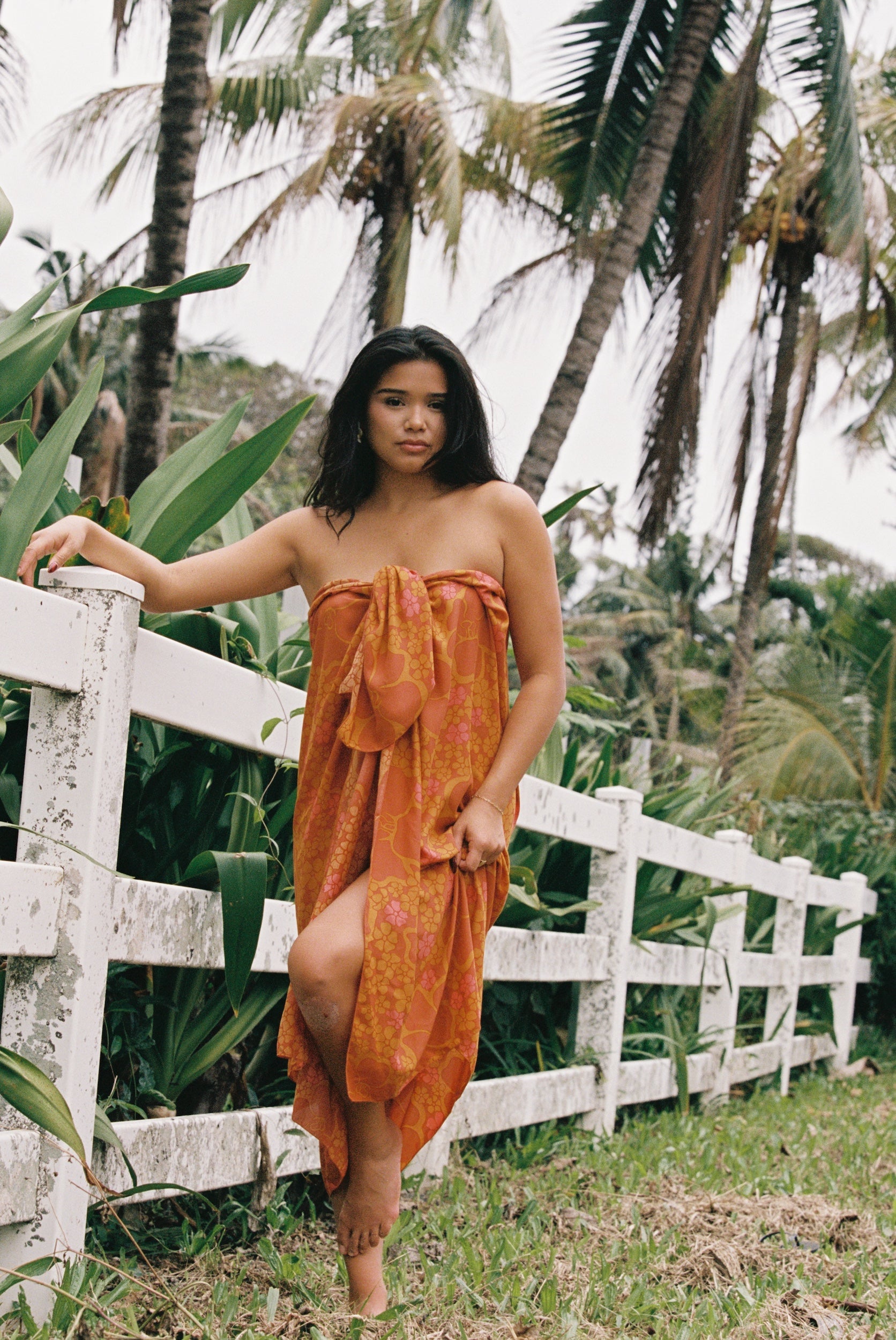 woman with brown hair wearing an orange puakenikeni pareo