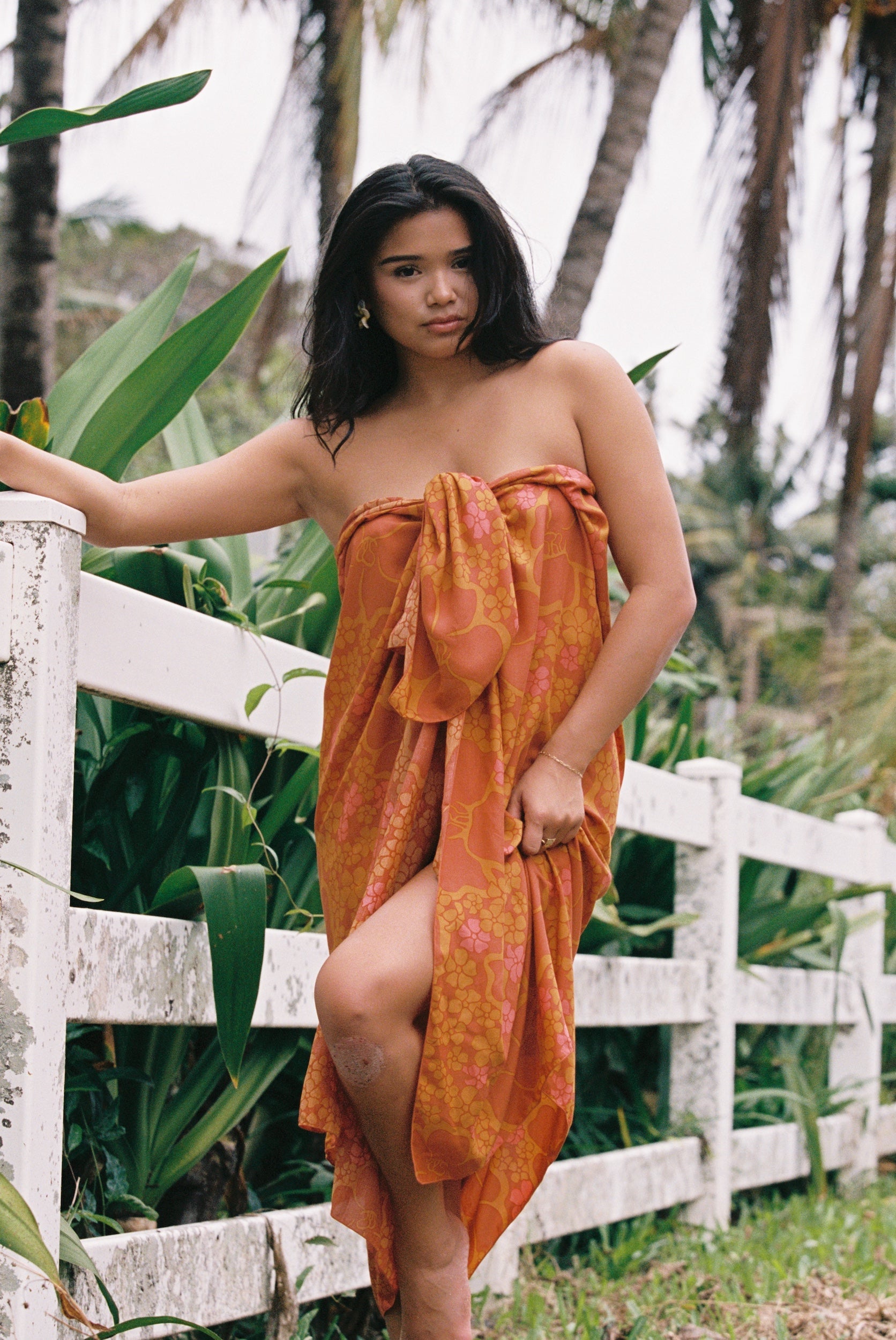 woman with brown hair wearing an orange puakenikeni pareo