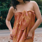 woman with brown hair wearing an orange puakenikeni pareo