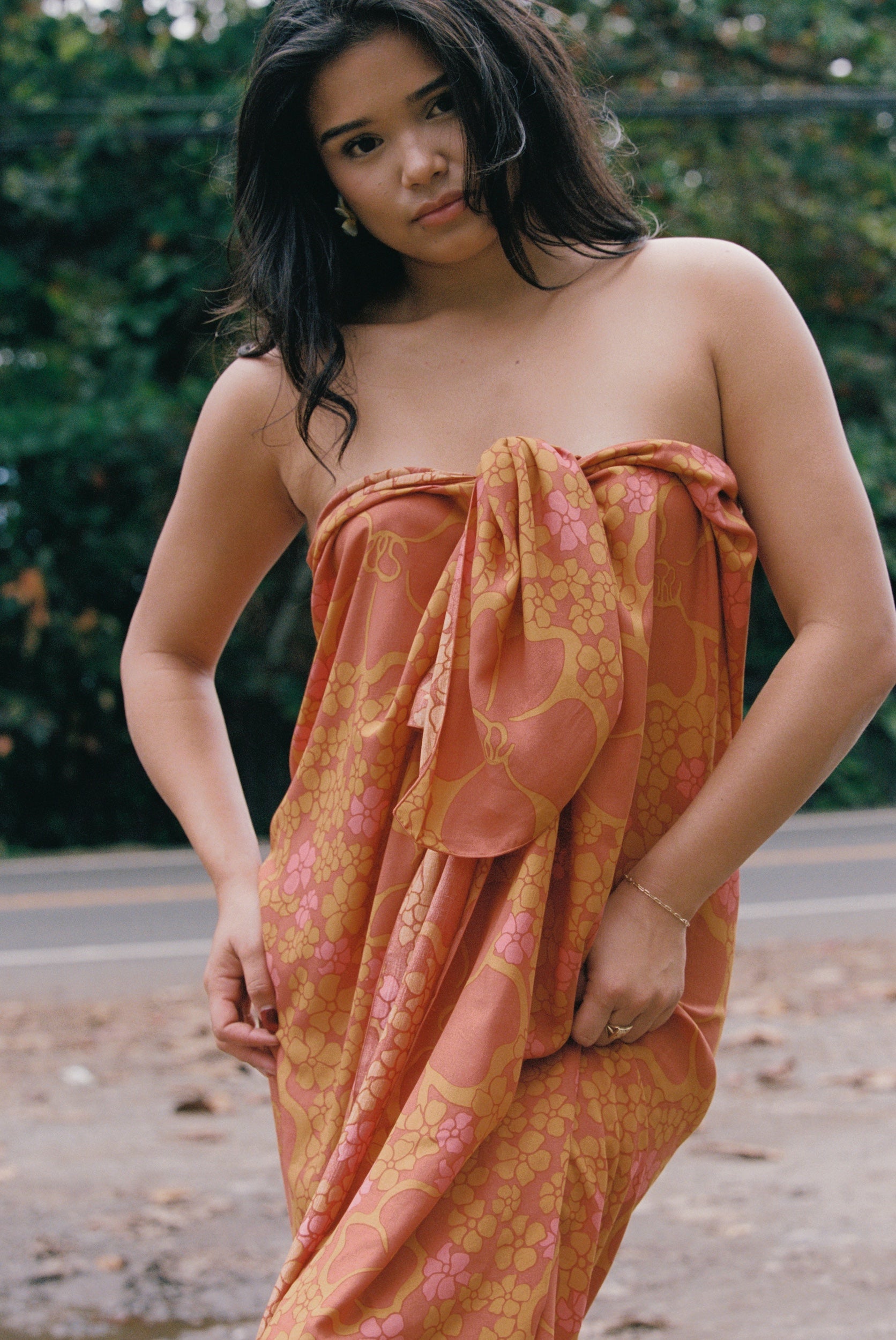 woman with brown hair wearing an orange puakenikeni pareo