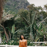 woman with brown hair wearing an orange puakenikeni pareo