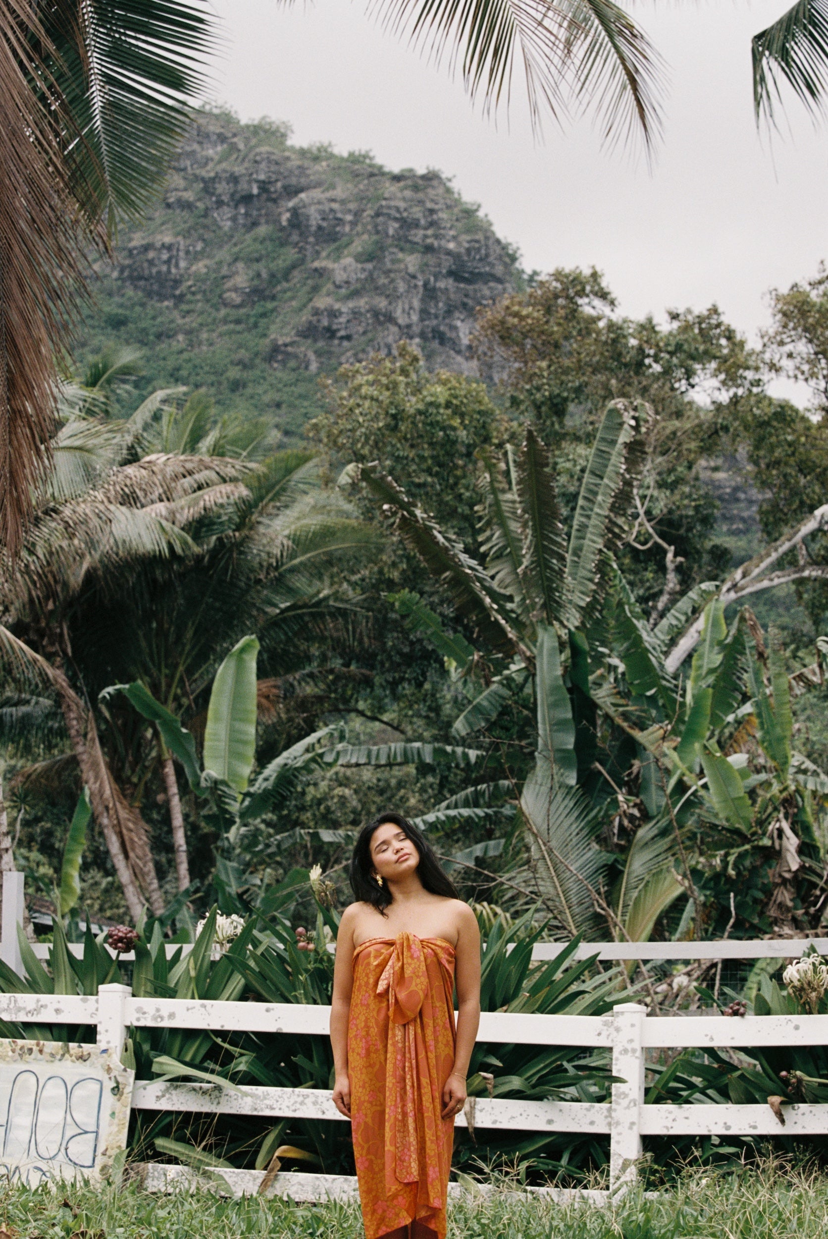 woman with brown hair wearing an orange puakenikeni pareo