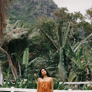 woman with brown hair wearing an orange puakenikeni pareo