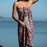 woman with brown hair wearing a teal pareo wrap with shell and pua print 