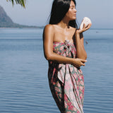 woman with brown hair wearing a teal pareo wrap with shell and pua print 