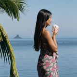 woman with brown hair wearing a teal pareo wrap with shell and pua print 